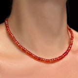 A close-up of a 16" blood orange faceted padparadscha sapphire necklace on a model's neck.