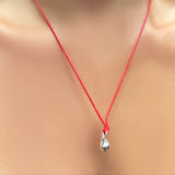 A red cord necklace holding a recyceld sterling silver mini molten drop charm on a model's neck.