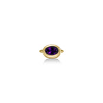 A 14K yellow gold oval ring, with a bezel set faceted amethyst gemstone, sits on a white background with drop shadow.