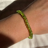 Peridot rondelle beaded gemstone bracelet on a model's wrist.