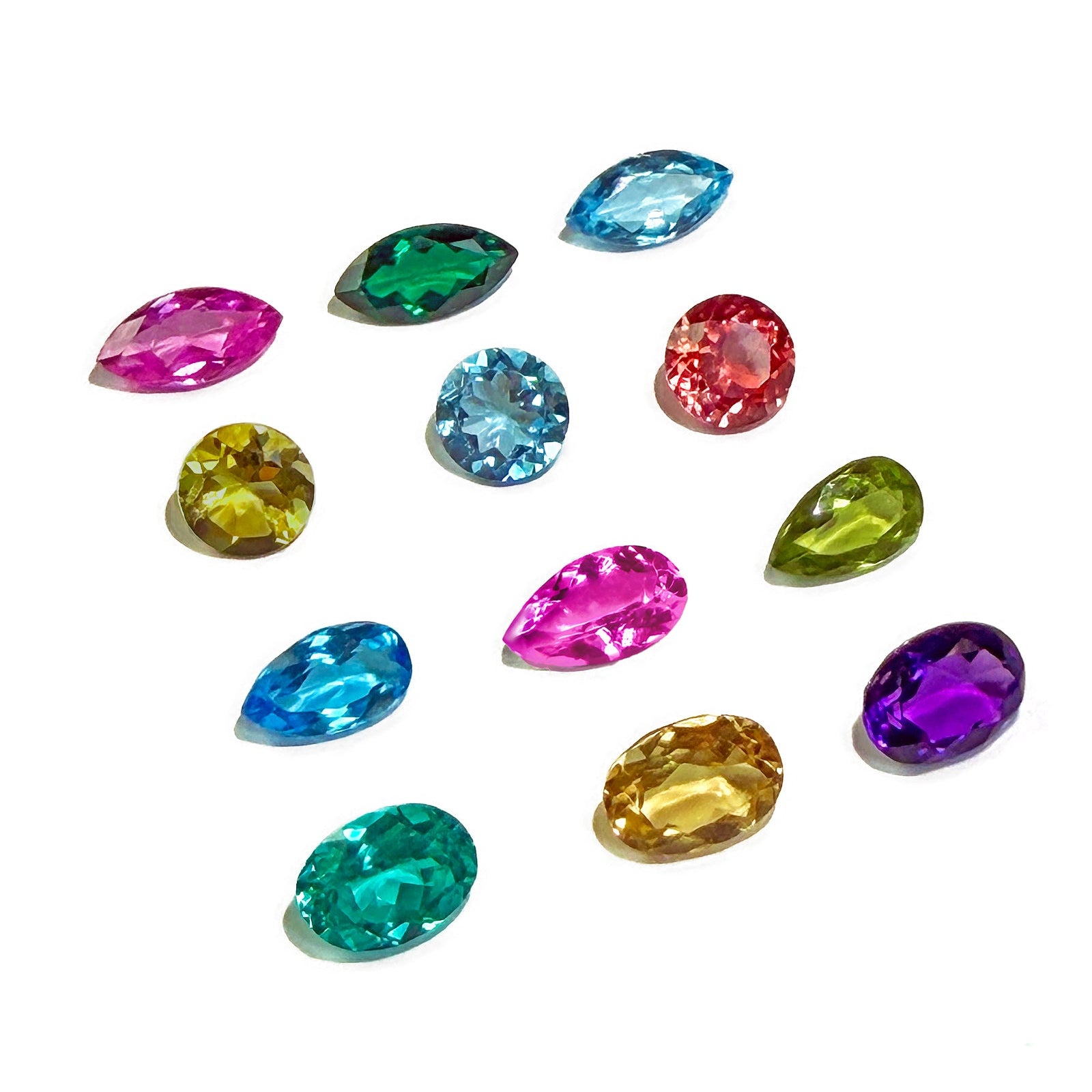A grid of 12 special, one-of-a-kind semi-precious gemstones of different shapes and colors on a white background.