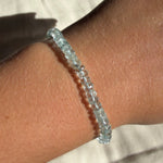 A single faceted aquamarine beaded bracelet on a model's wrist.