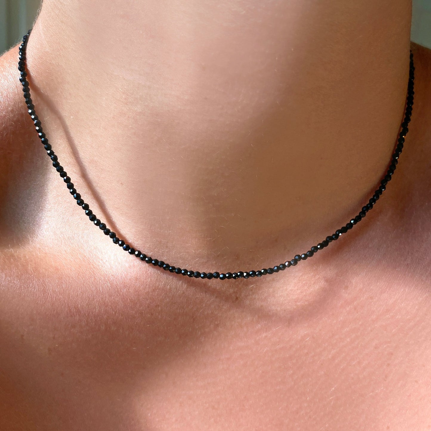 Shimmering beaded necklace made of 2mm faceted opals in shades of black on a gold linking lobster clasp.