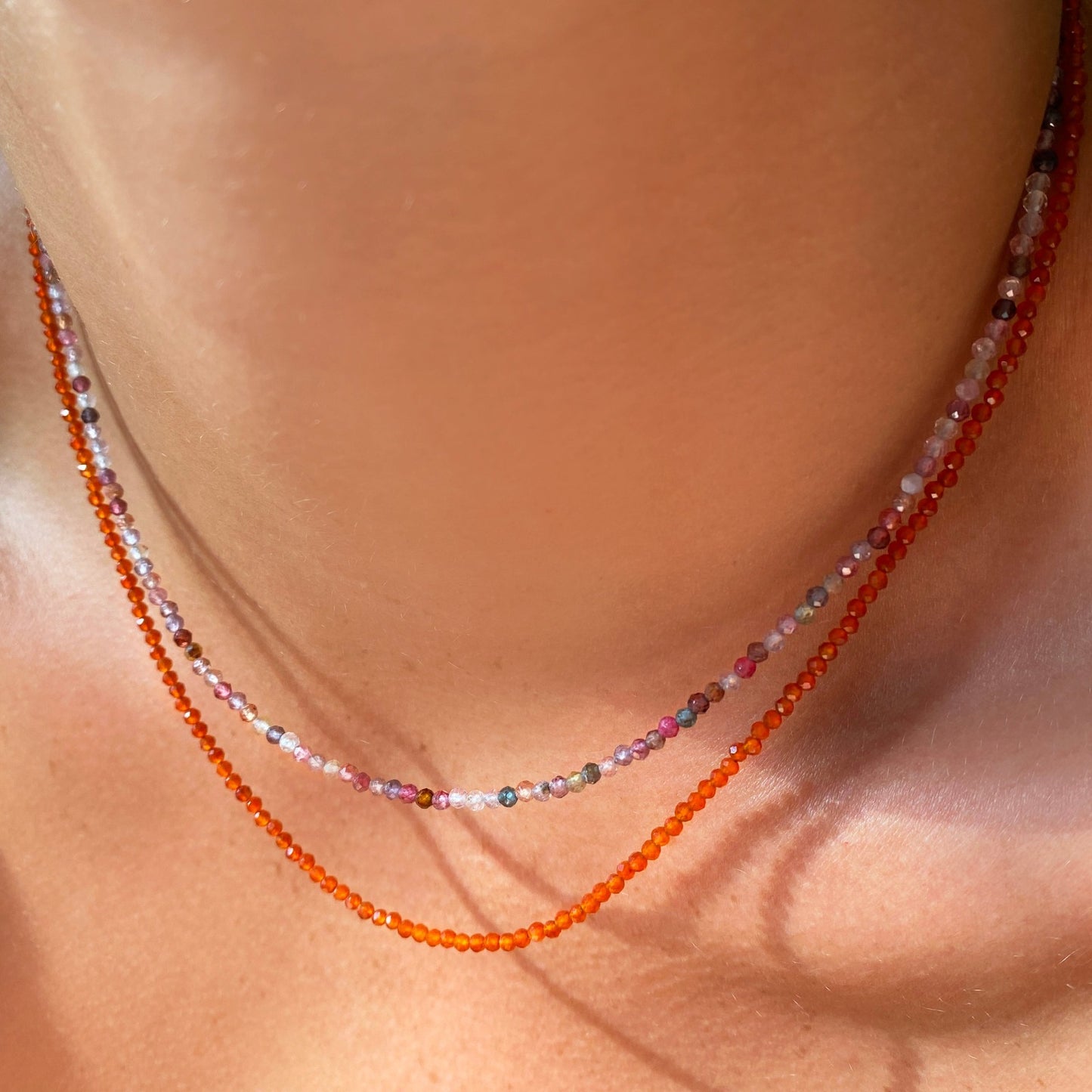 Two shimmering beaded necklaces made of 2mm faceted opals in shades of pink and orange on a gold linking lobster clasp.