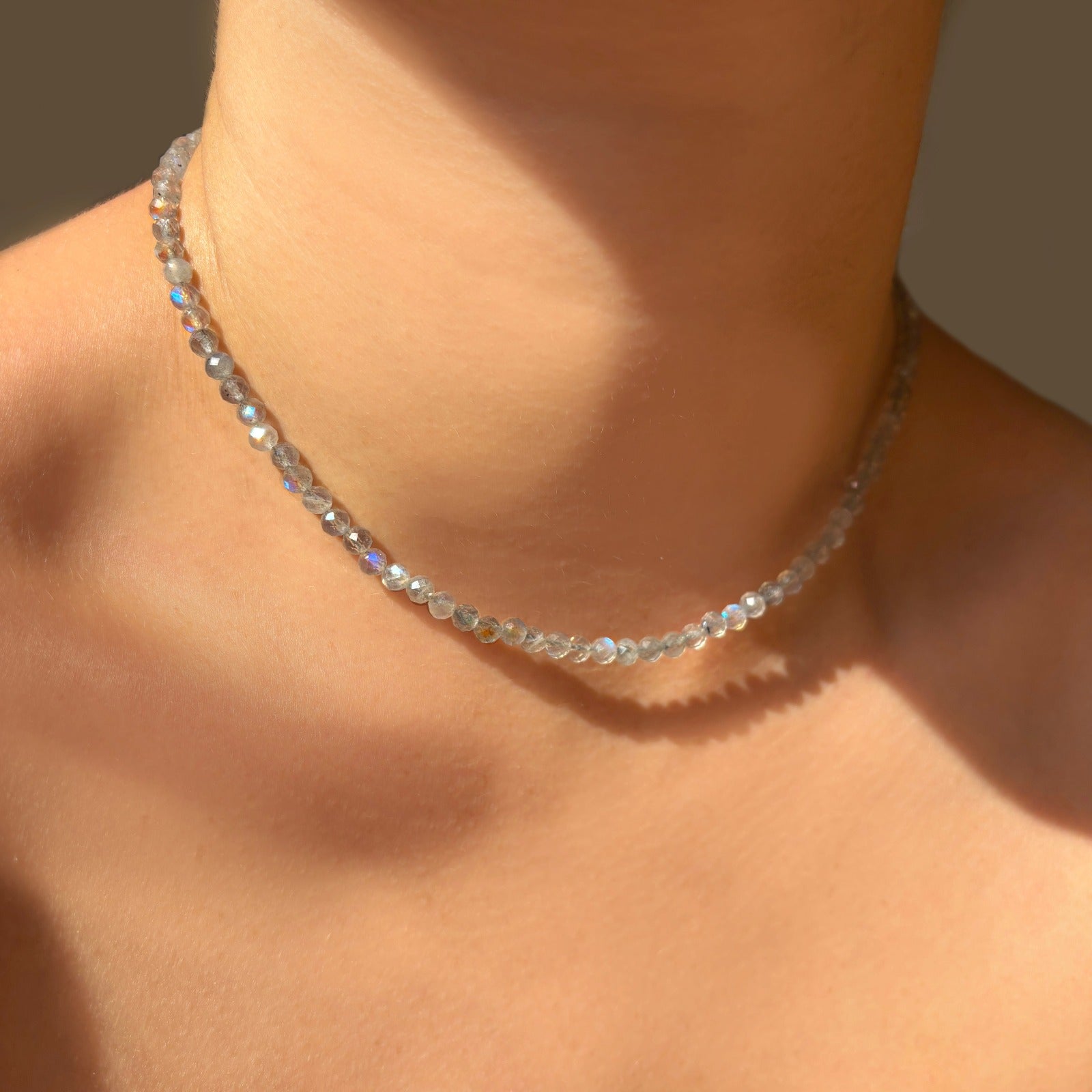 Shimmering beaded necklace made of 4mm faceted rounded opals in shades of clear white on a gold linking oval clasp.