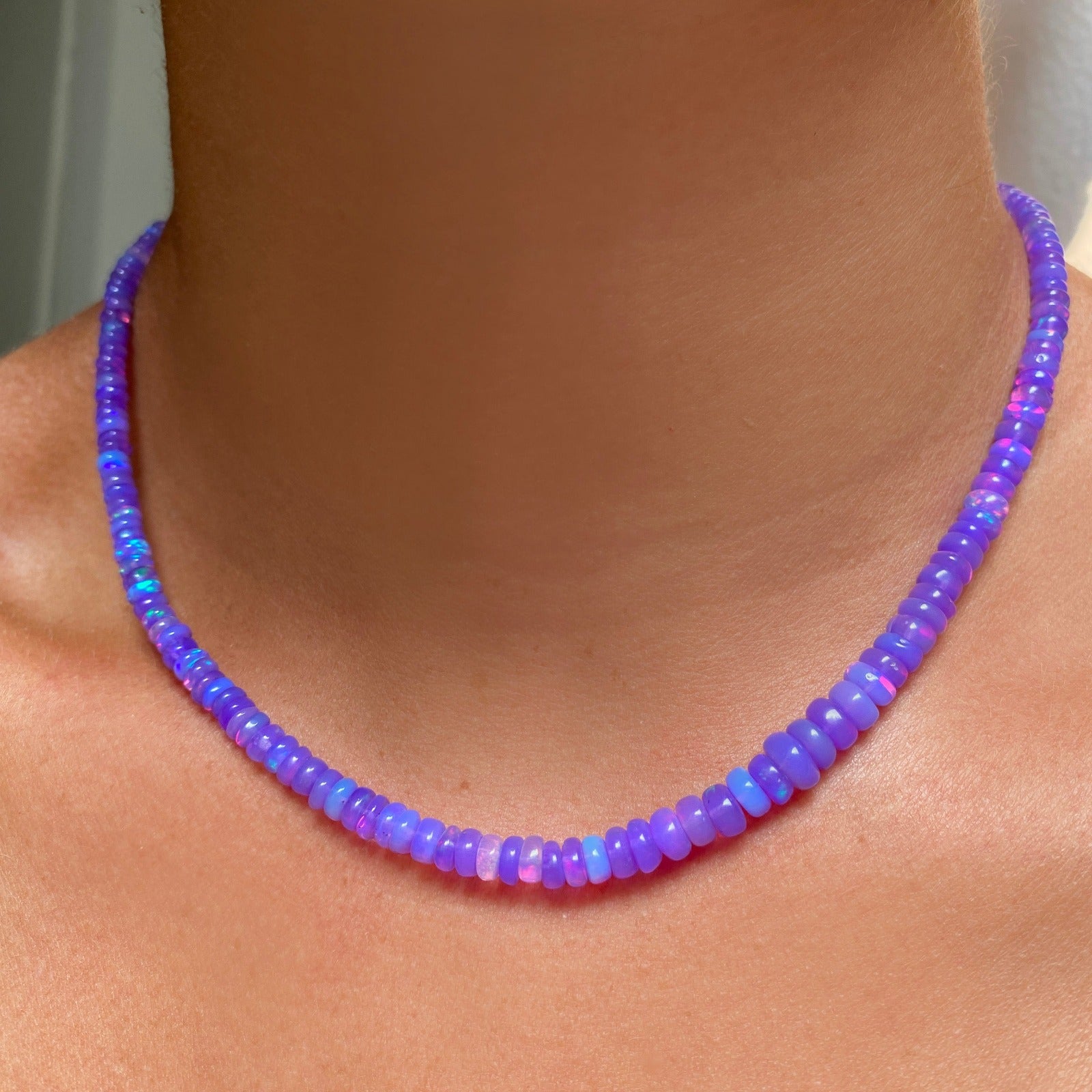 Shimmering beaded necklace made of smooth opal rondels in shades of violet on a slim gold oval clasp.