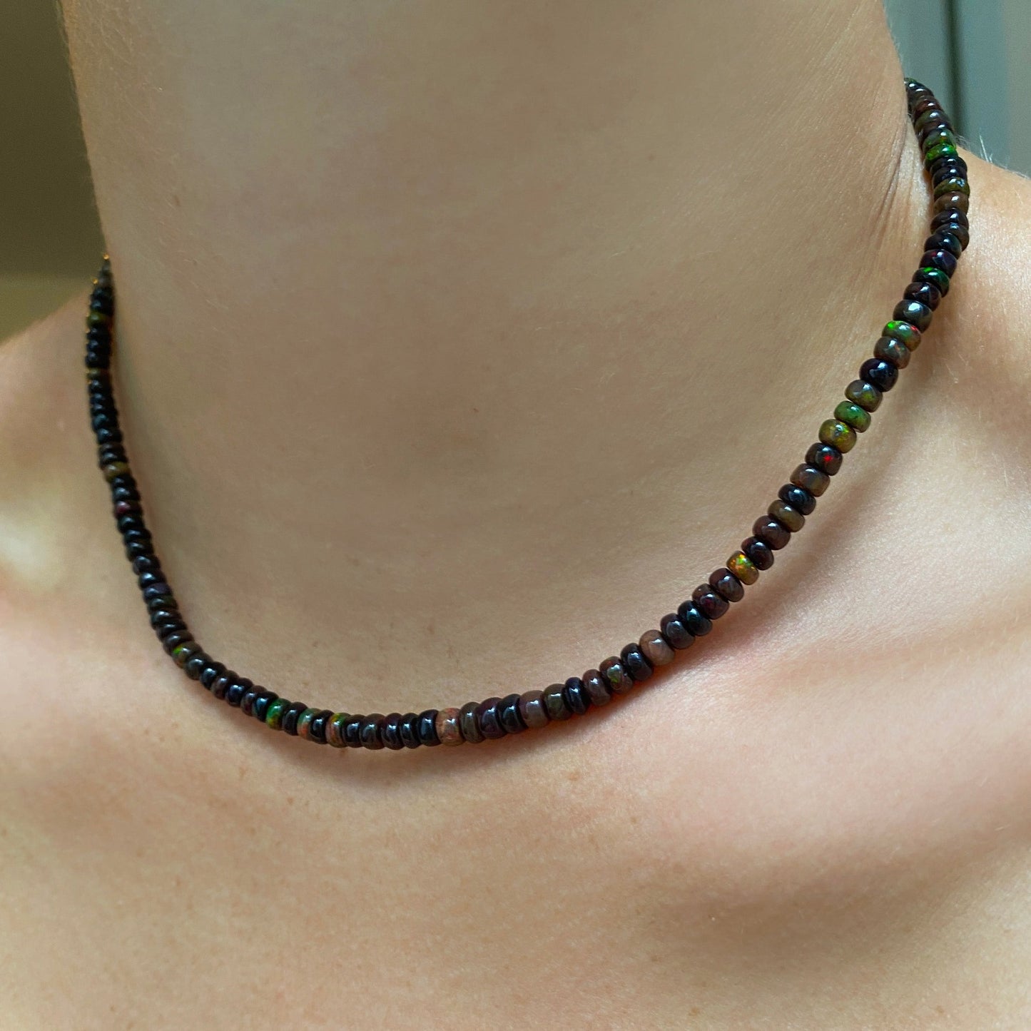 Shimmering beaded necklace made of faceted opals in shades of brown on a gold linking ovals clasp. 