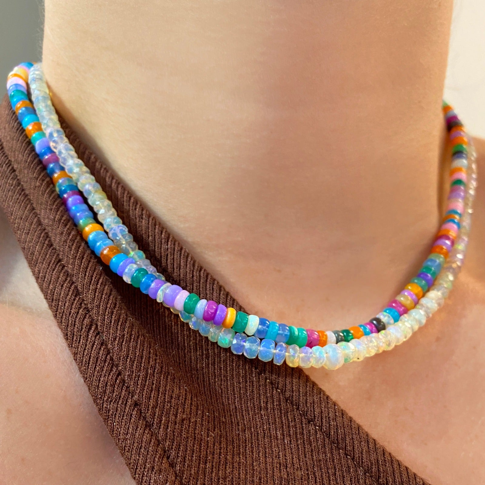 Shimmering beaded necklace made of smooth opal rondels in shades of fiery blues, hot pink, teal, and orange on a slim gold oval clasp. 
