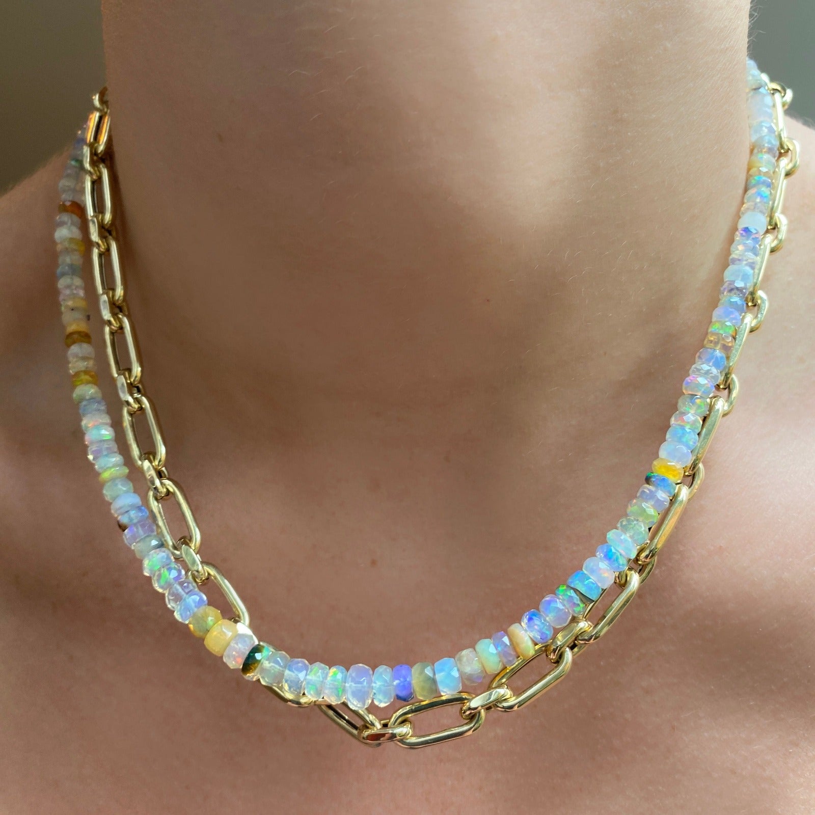 Shimmering beaded necklace made of faceted opals in shades of white, clear, and yellow on a gold linking ovals clasp. Styled on a neck layered with the diamond cut link chain necklace.