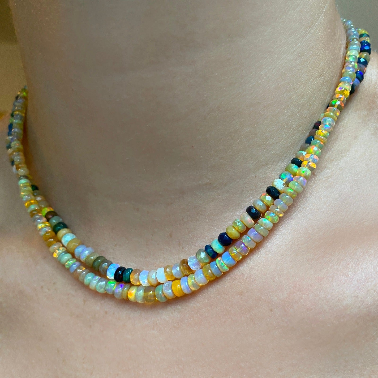 Shimmering beaded necklace made of faceted opals in shades of yellow, white, clear, brown, and black on a gold linking ovals clasp.