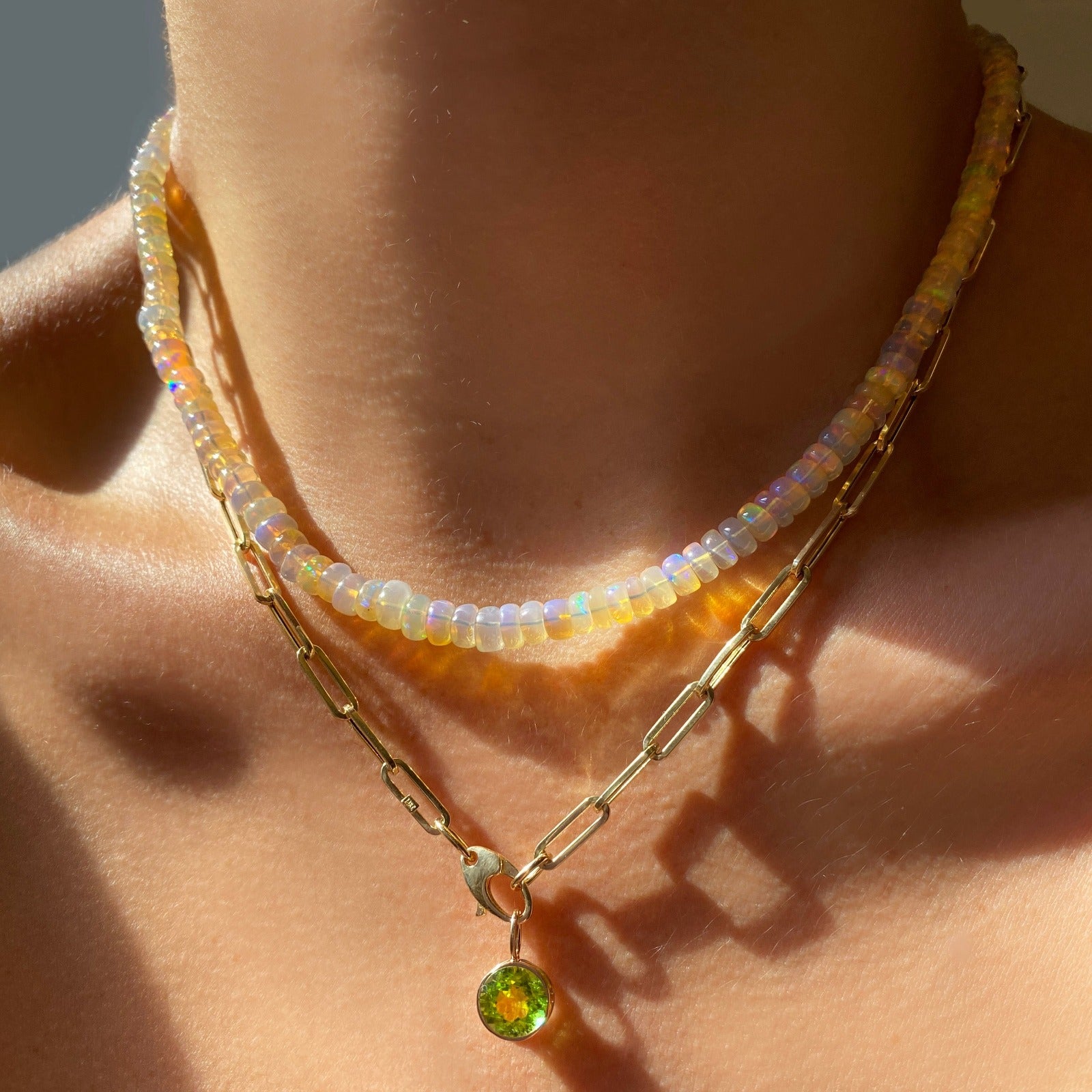 Shimmering beaded necklace made of smooth opal rondels in shades of light yellow and clear opals on a slim gold lobster clasp. Styled on a neck layered with a paperclip chain necklace and round solitaire charm.