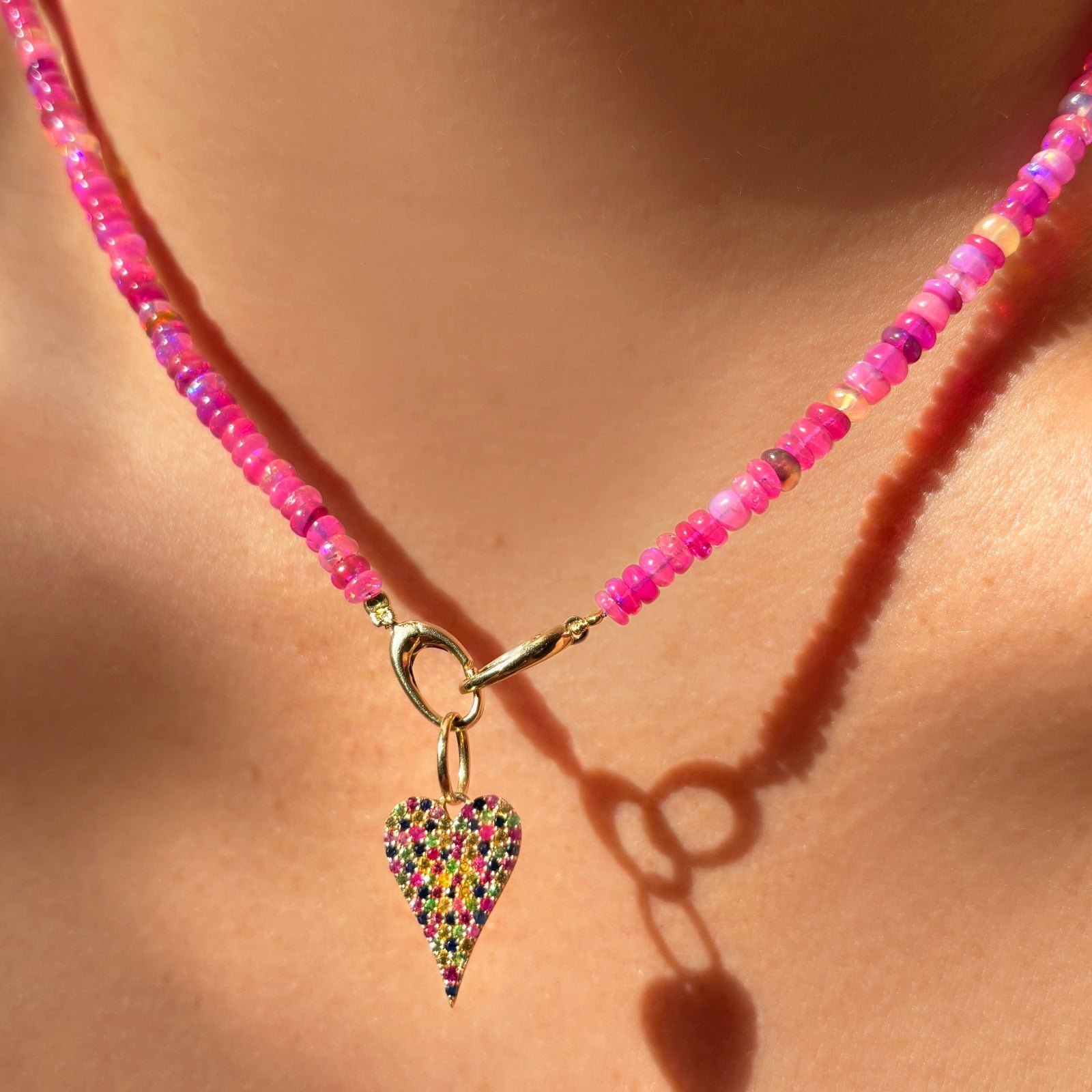 Shimmering Fuchsia Opal Necklace of smooth opals with various shades of pink, styled on a neck with a Medium Pavé Heart Charm 