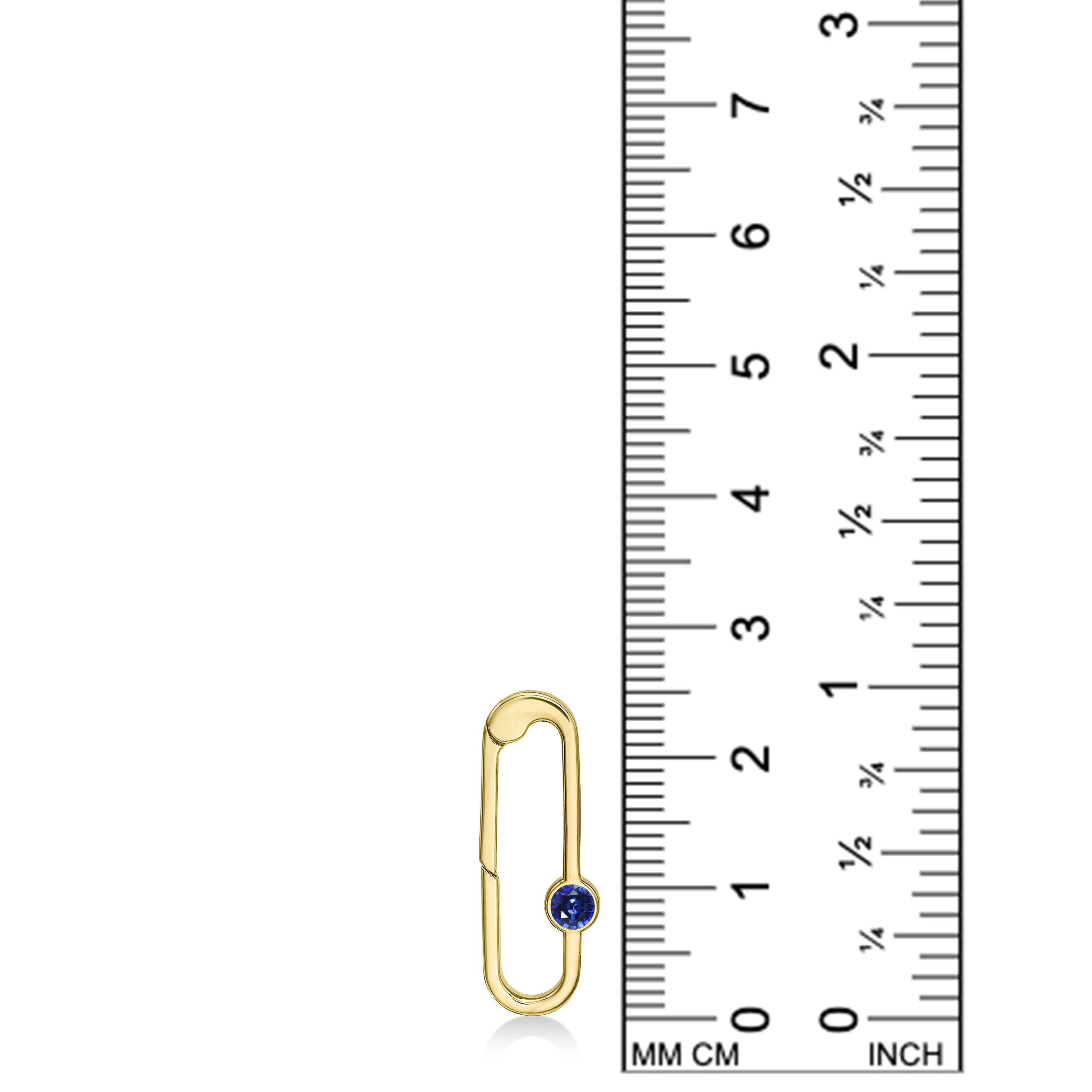 14K yellow gold charm lock with a sapphire stone, set against a ruler for scale, on a white background.
