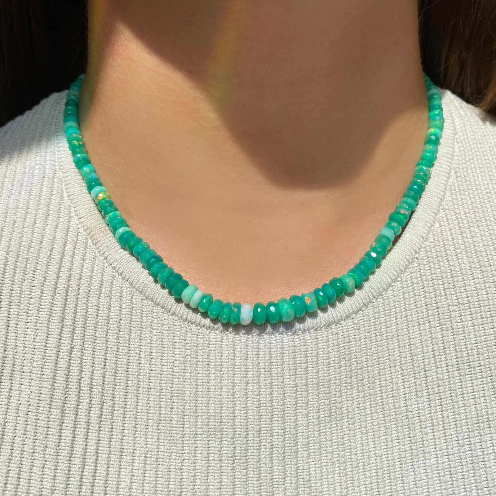 Shimmering beaded necklace made of faceted opals in shades of green on a gold linking ovals clasp.