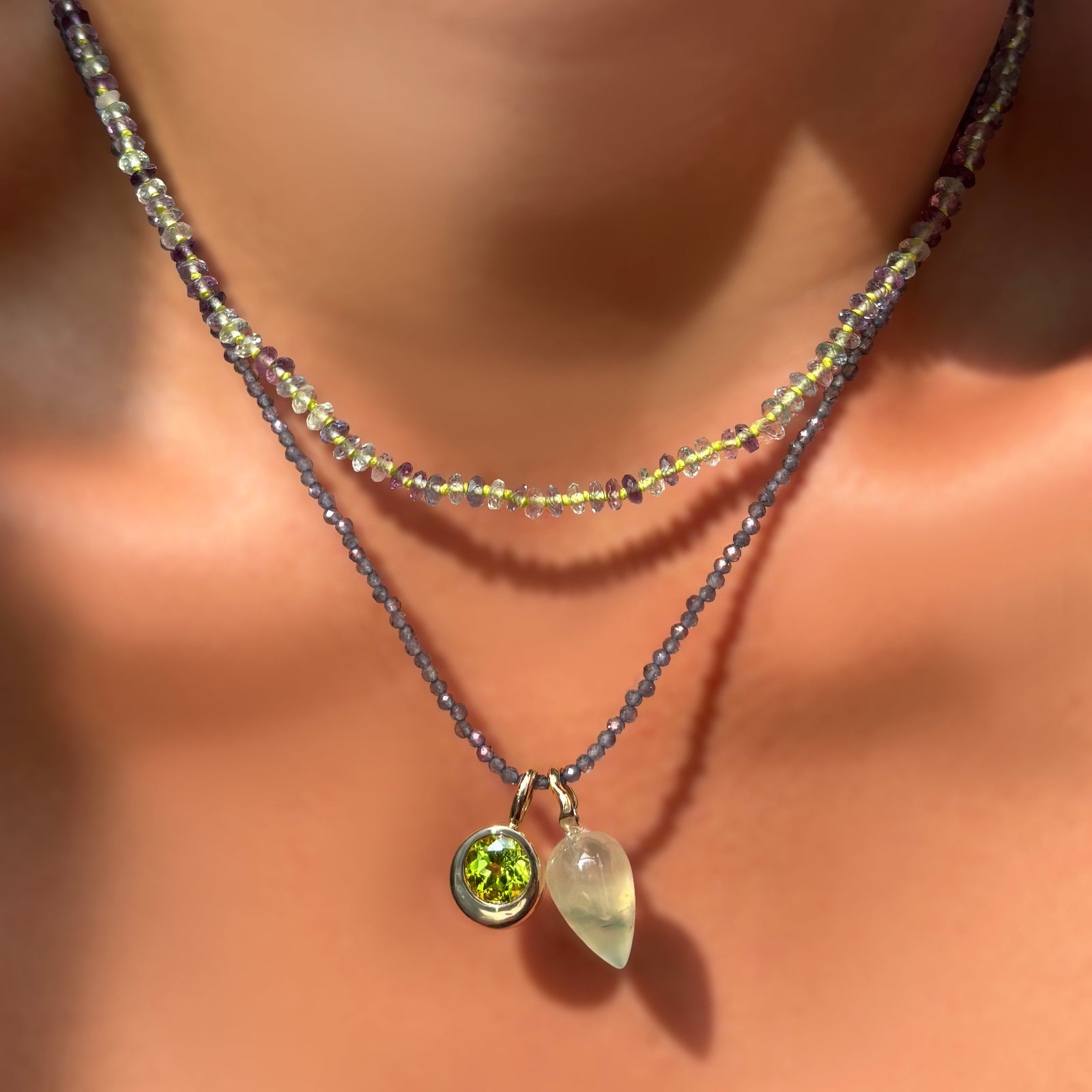 Faceted Fluorite on Neon necklace layered over an iolite slim gemstone necklace with round molten charm with peridot, and prehnite drop charm