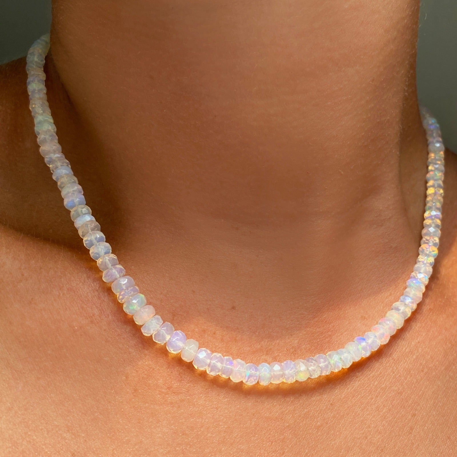 Shimmering beaded necklace made of faceted opals in shades of clear opals on a gold linking ovals clasp.