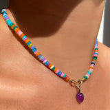 Amethyst acorn drop charm. Styled on a neck hanging from oval clasps of a beaded necklace