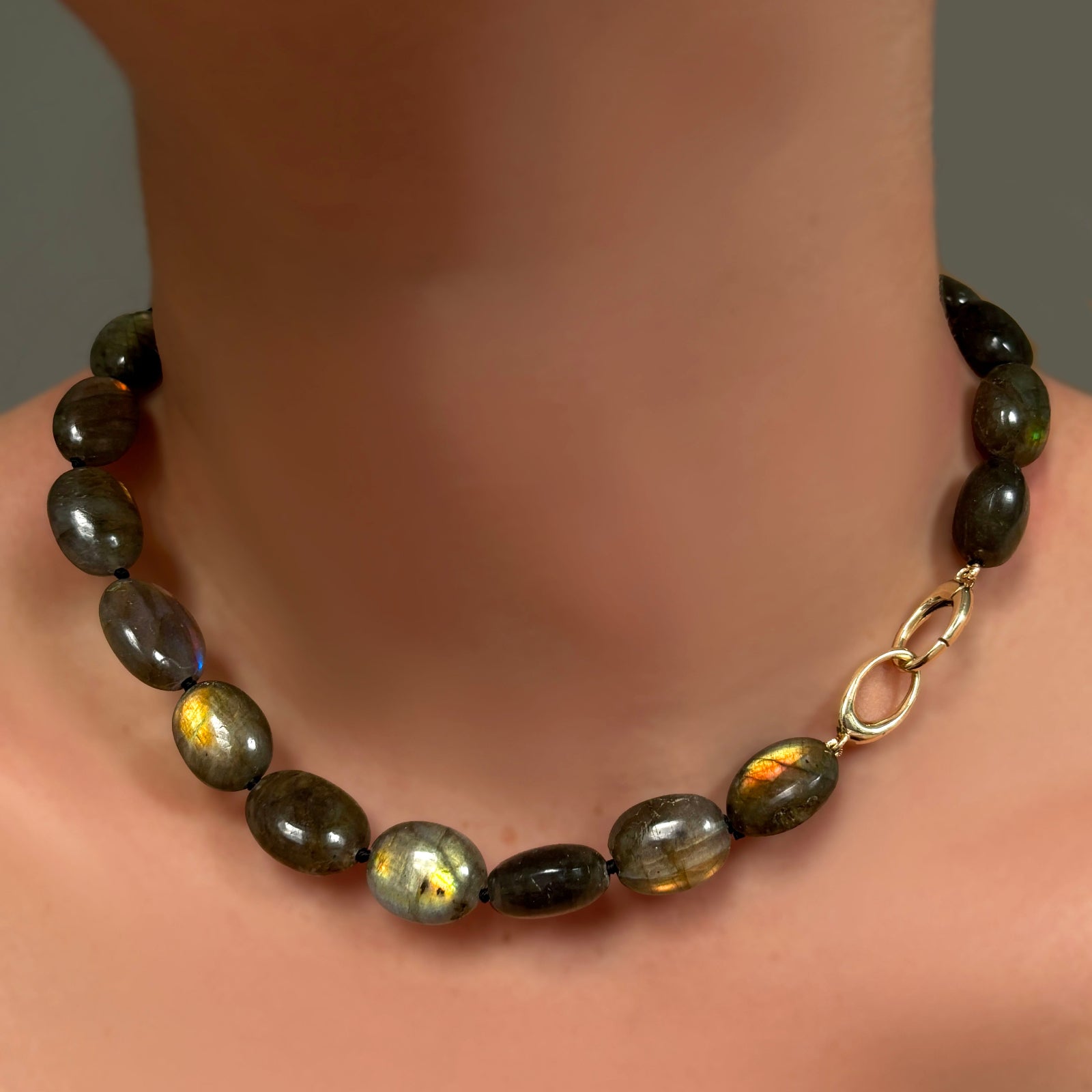 Gemmy and flashy labradorite oval beads on a linking ovals clasp on a model's neck.