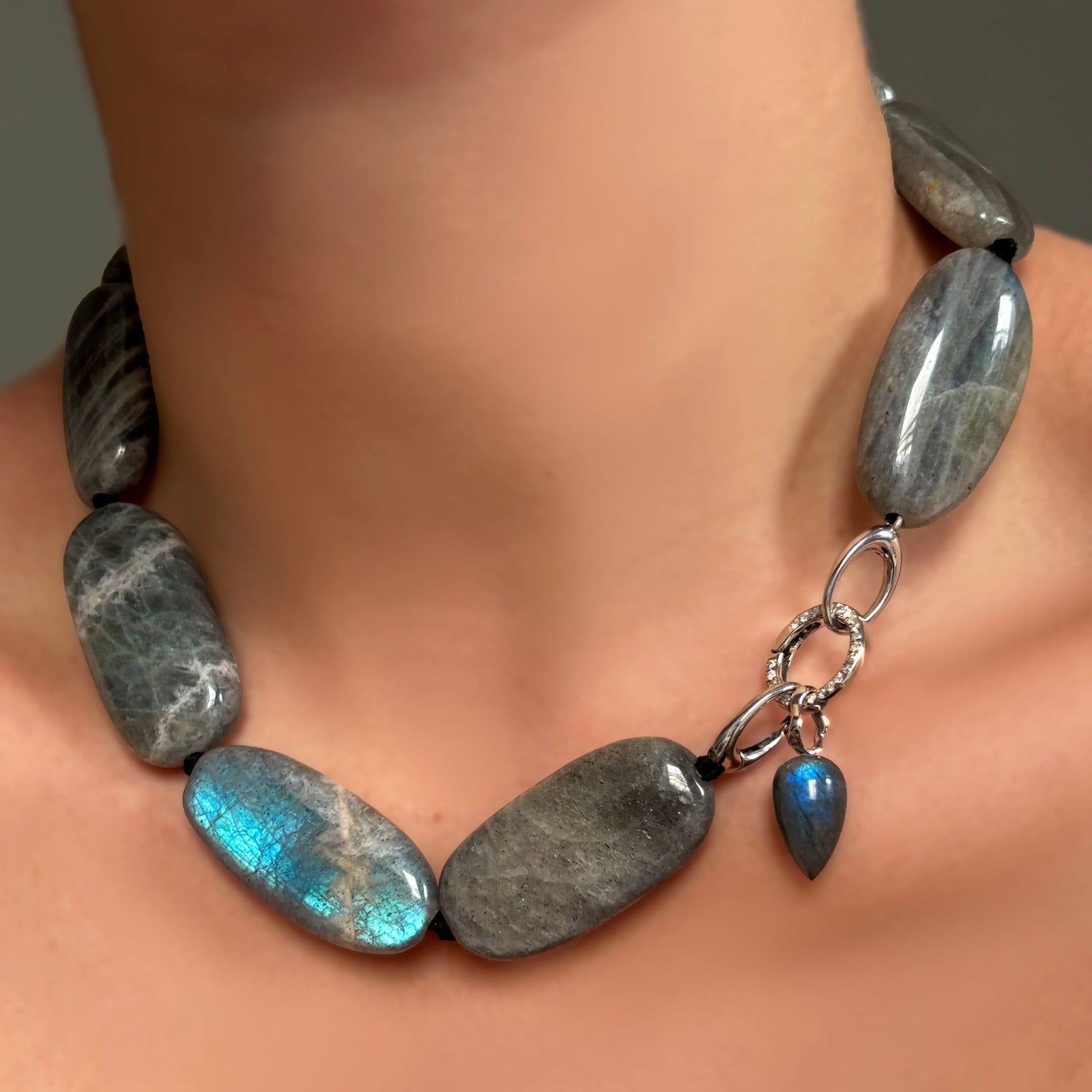 Labradorite Long Oval Necklace with Round pavé face charm lock and Labradorite drop charm on recycled white gold ripple bale on a model's neck.