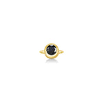 A gold ring featuring a bezel-set round black gemstone, centered on a clean white background with a soft reflection below.
