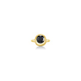 A gold ring featuring a bezel-set round black gemstone, centered on a clean white background with a soft reflection below.