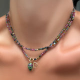 Two multi tourmaline necklaces on a model's neck, one with a ruby zoisite drop charm and letter P charm in recycled yellow gold..