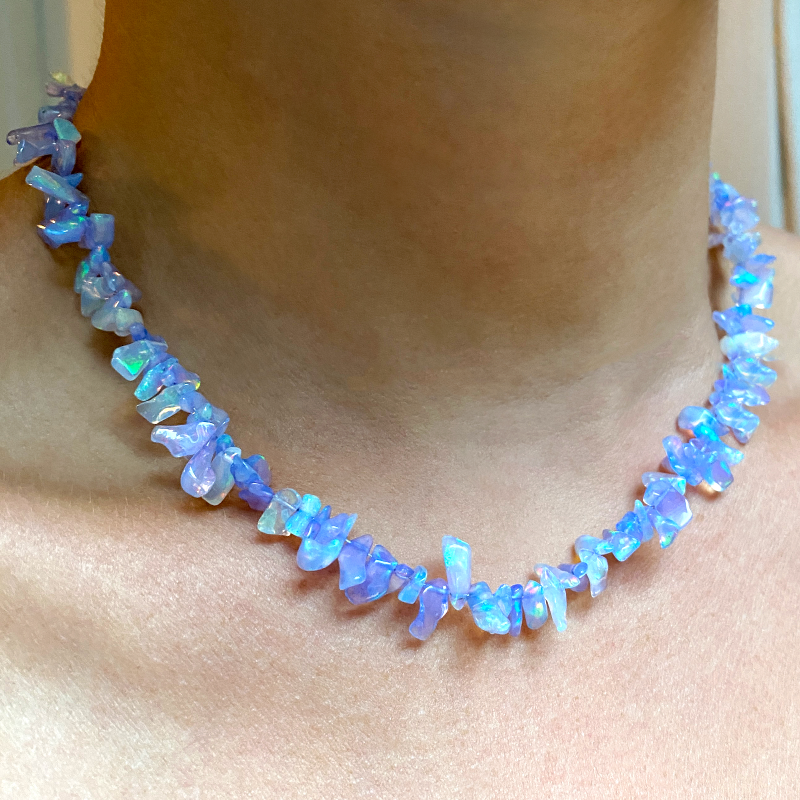 Shimmering beaded necklace made of rough opals in shades of pastel blue on a gold linking ovals clasp.