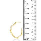 A photo of an undulating hoop earring next to a ruler showing that is is 3.3cm in height. It is made of 14k yellow gold with a rippling shape that is a play on a classic gold hoop earring. It is studded with small diamonds that catch the light and shimmer.