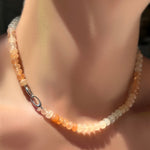 Ombré peachy strawberry quartz rondelle necklace on a sterling silver clasp turned towards the front on a model's neck.