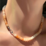 Ombré peachy strawberry quartz rondelle necklace on a sterling silver clasp turned towards the front on a model's neck.