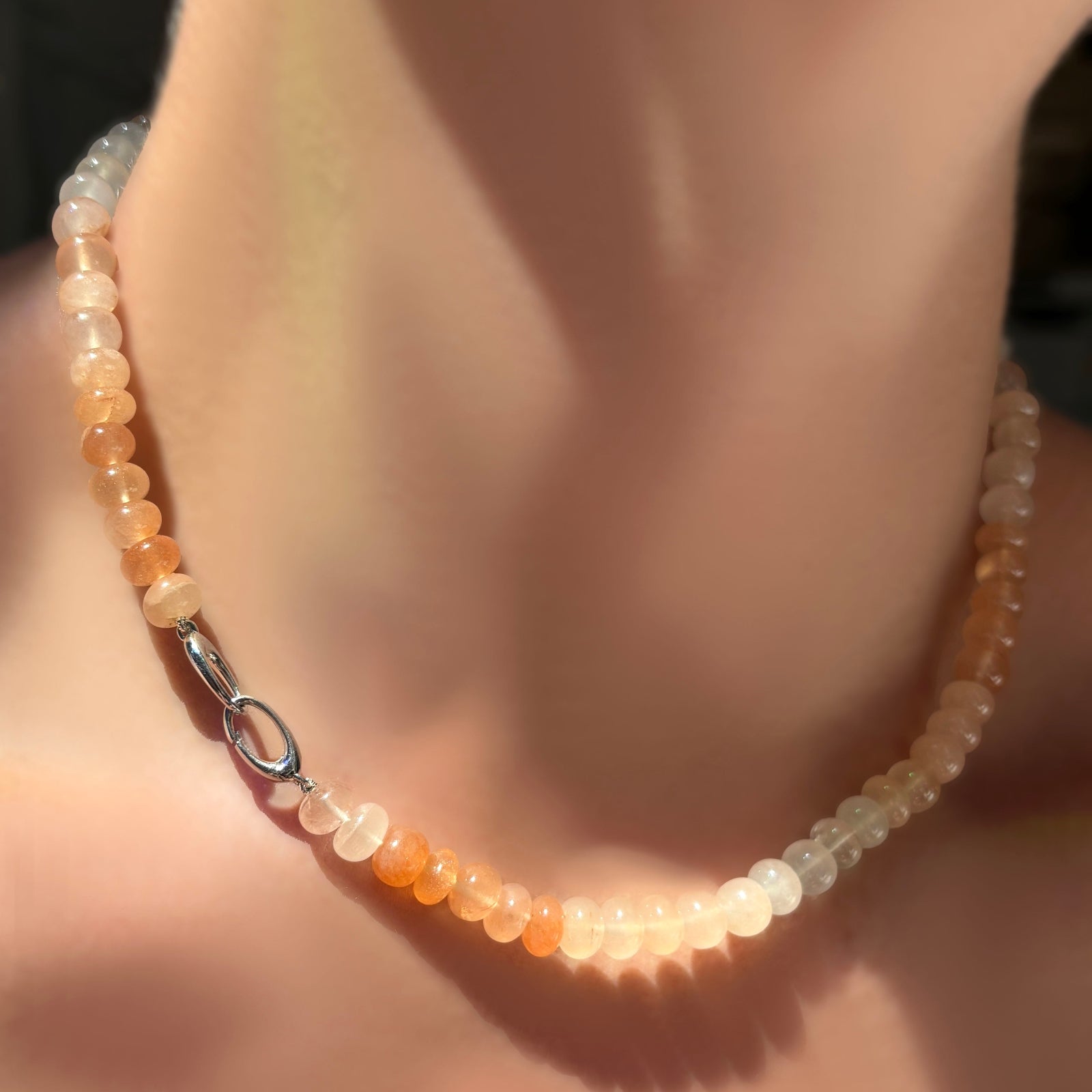 Ombré peachy strawberry quartz rondelle necklace on a sterling silver clasp turned towards the front on a model's neck.