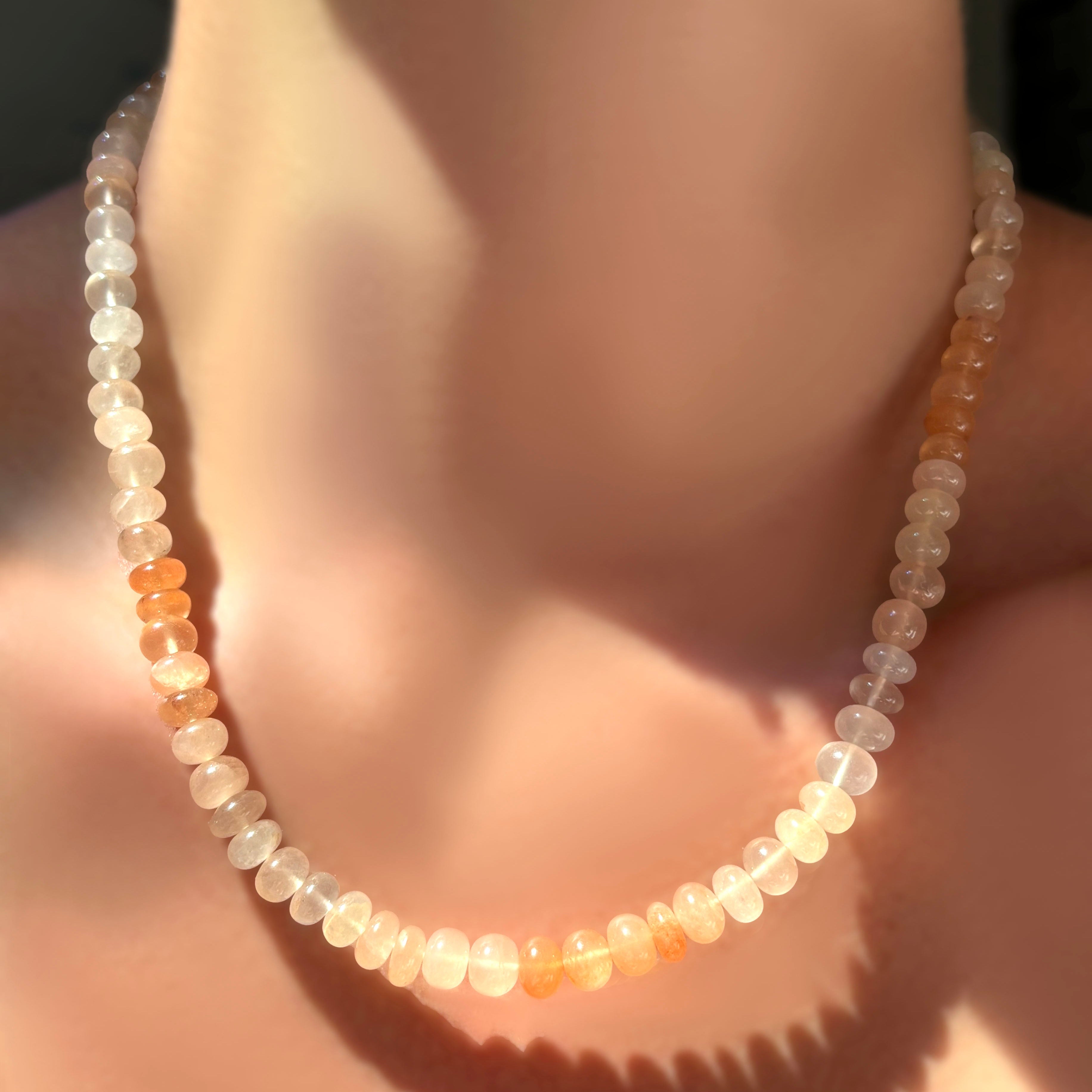 Ombré peachy strawberry quartz rondelle necklace on a model's neck.