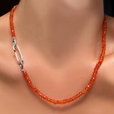 An AMANDA PEARL faceted carnelian necklace on a recycled sterling silver evolution clasp holding a recycled sterling silver paperclip charm lock with carnelian cabochon.