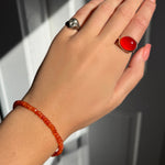 A model wearing an AMANDA PEARL faceted carnelian beaded bracelet along with a recycled sterling silver molten skull pinky ring and pebble ring with carnelian cabochon.
