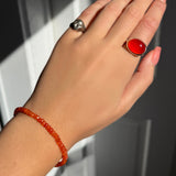 A model wearing an AMANDA PEARL faceted carnelian beaded bracelet along with a recycled sterling silver molten skull pinky ring and pebble ring with carnelian cabochon.