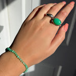 Model wearing an AMANDA PEARL recycled sterling silver molten ring, pebble ring with chrysoprase cabochon, and faceted chrysoprase beaded bracelet.