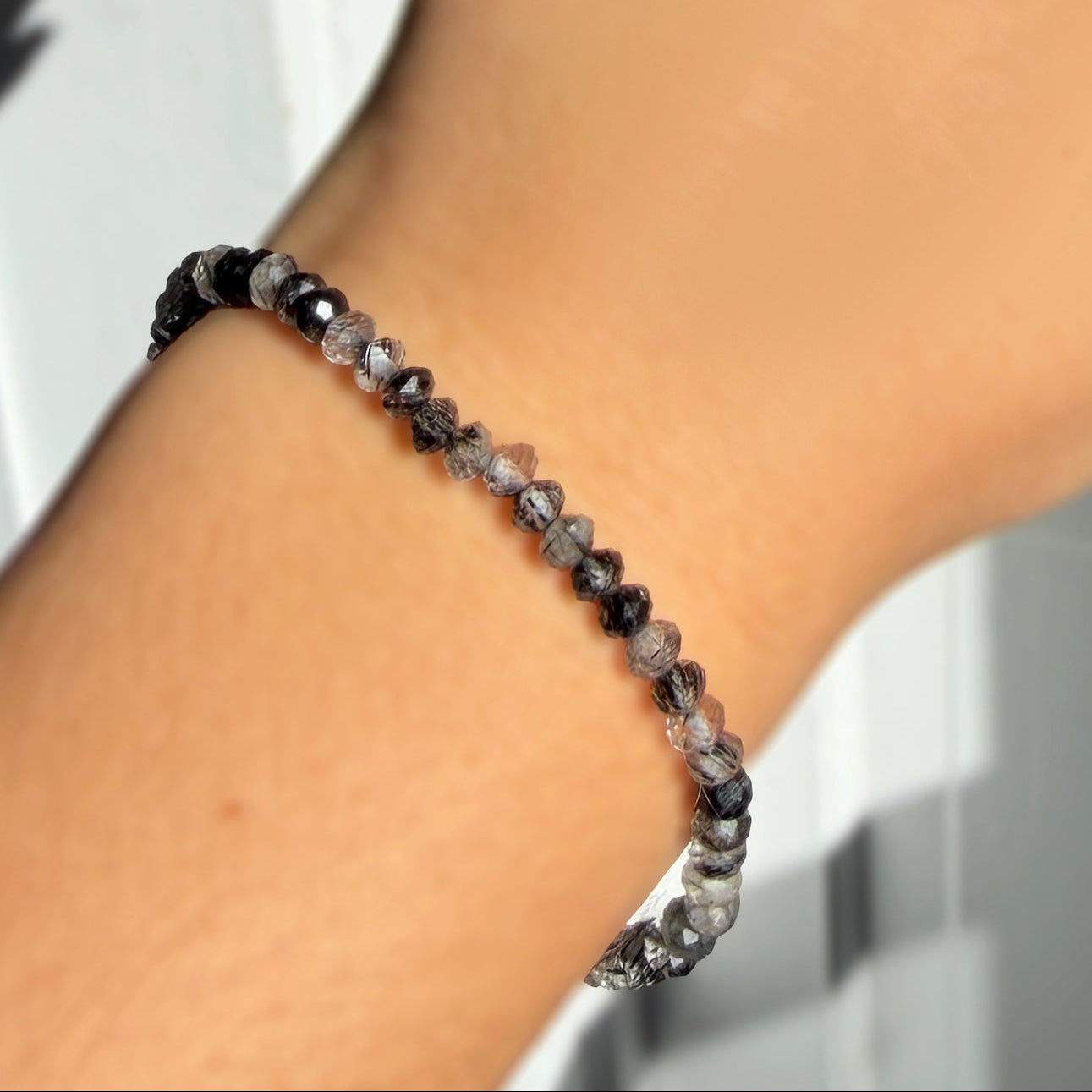 A  model wearing a faceted rutilated quartz beaded bracelet from AMANDA PEARL.