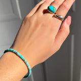 A model wearing an AMANDA PEARL turquoise rondelle bracelet, recycled sterling silver pebble ring with turquoise cabochon, and molten ring.
