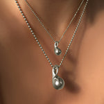 AMANDA PEARL recycled sterling silver mini molten drop charm on diamond cut bead chain over a molten drop charm on bead chain on a model's neck.
