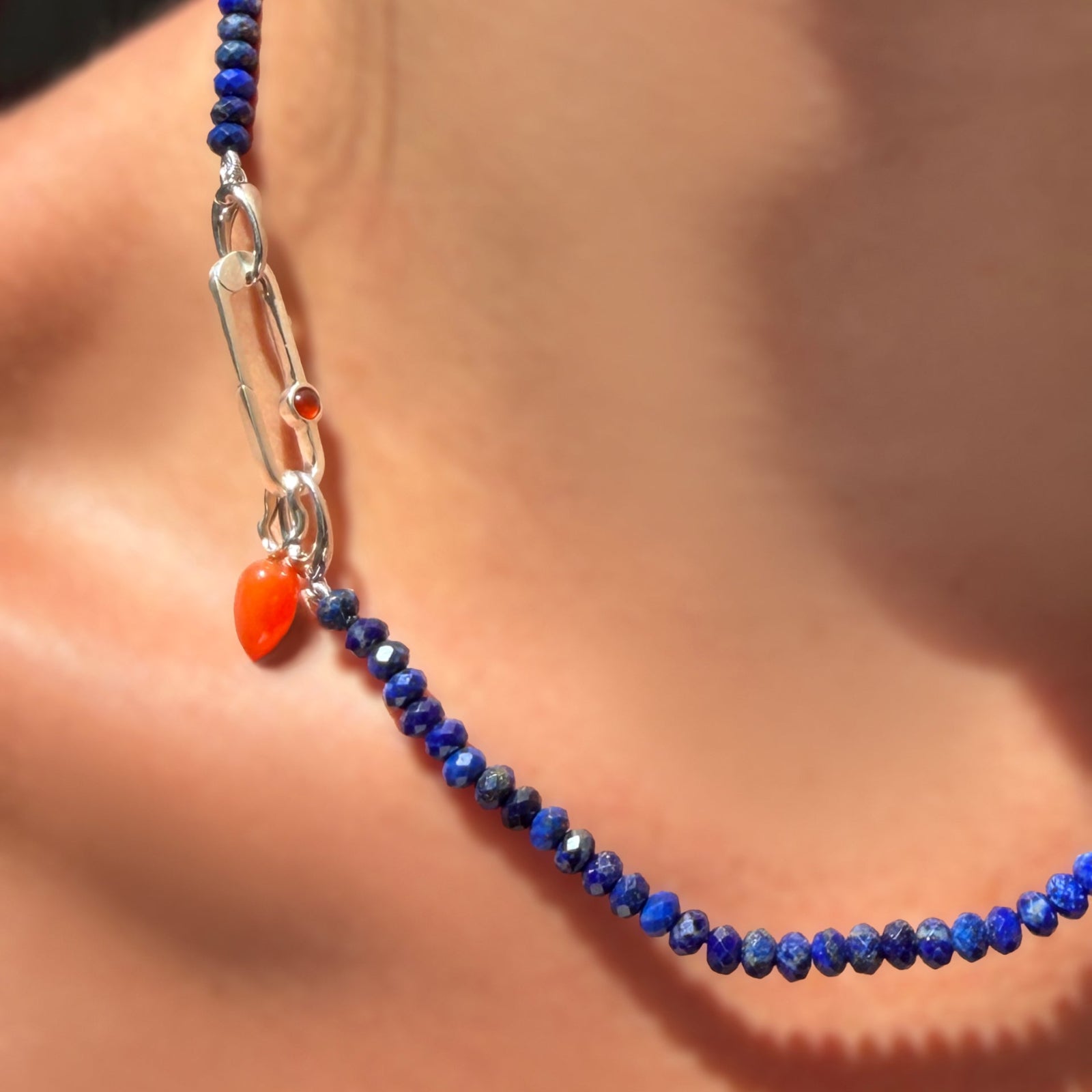 Faceted lapis rondelles on a sterling silver evolution clasp holding a paperclip charm lock with carnelian cabochon, holding a carnelian drop charm with sterling silver ripple bale.