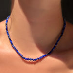 A faceted lapis necklace  with sterling silver evolution clasp on a model's neck.