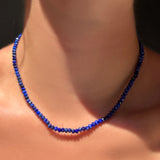 A faceted lapis necklace  with sterling silver evolution clasp on a model's neck.