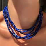 Multiple faceted lapis necklaces with sterling silver evolution clasps on a model's neck.