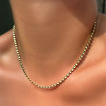 Tibet chain in 14k yellow gold on a model's neck.