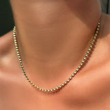 Tibet chain in 14k yellow gold on a model's neck.