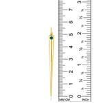 A quill spike charm from AMANDA PEARL in 14K recycled yellow gold with emerald sits against a ruler for scale.