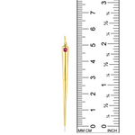 A quill spike charm from AMANDA PEARL in 14K recycled yellow gold with ruby sits against a ruler for scale.