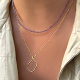 Amethyst slim gemstone necklace with diamond cut bead chain with letter "O" charm on a model's neck.