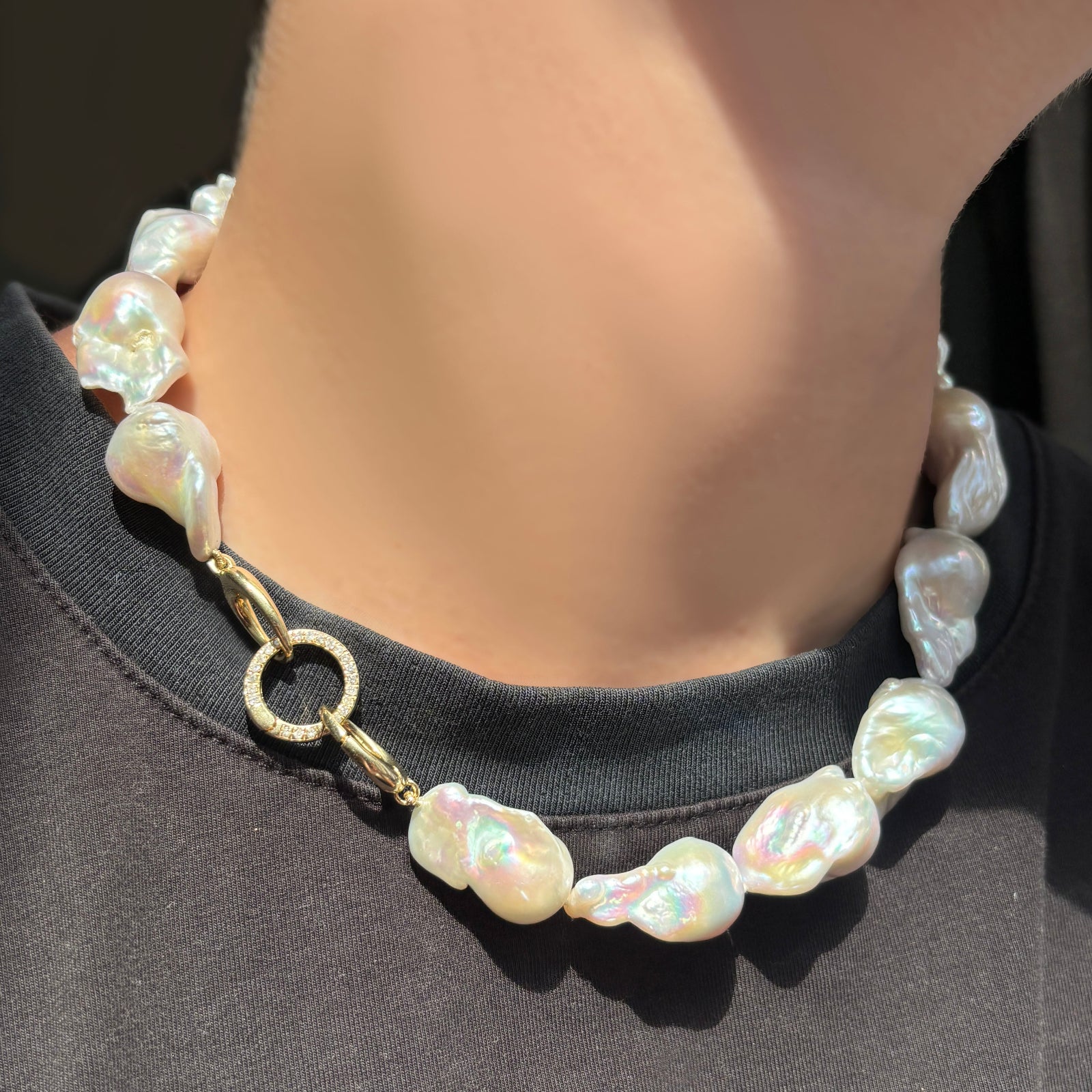 Baroque Pearl Collar with a round pavé face charm lock in the clasp on a model wearing a black tee.
