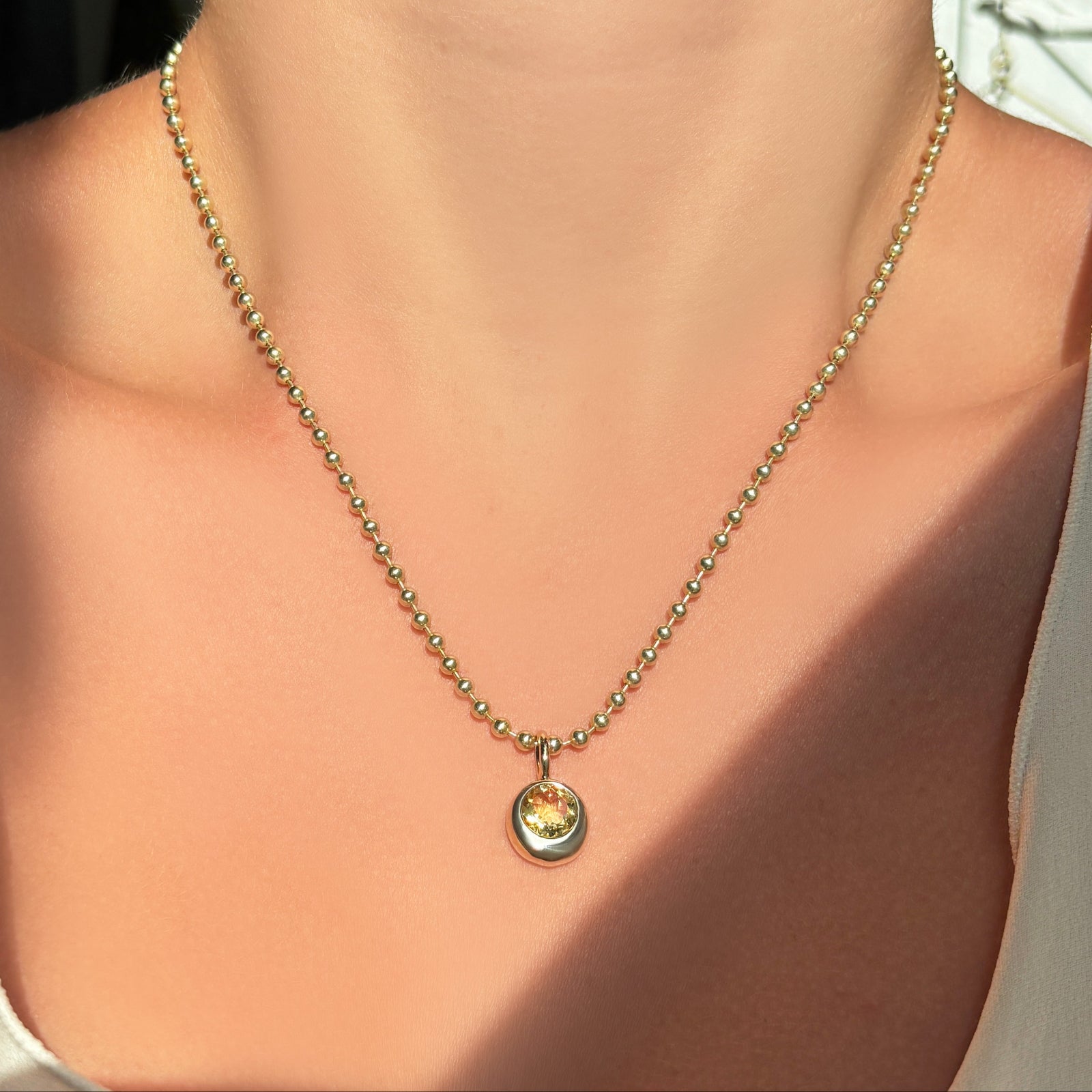 Bead chain Necklace with a molten solitaire charm with citrine worn by a person, focusing on the necklace.